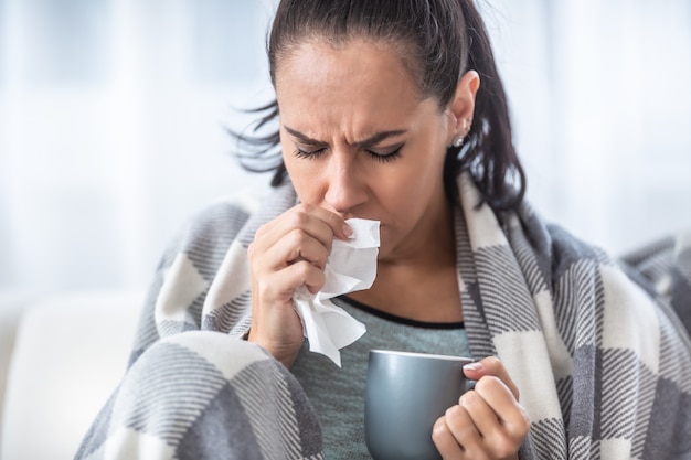 Femme avec une grippe tenant une tasse de thé chaud