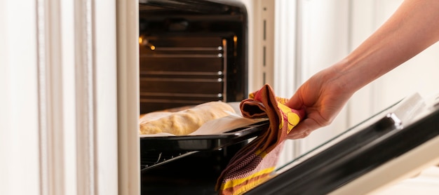 Une femme en gros plan les mains ouvrent le four et sortent des aliments cuits frais à la maison