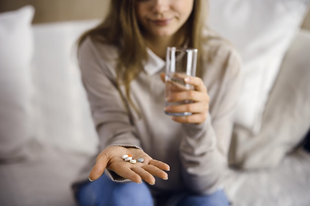 Femme en gros plan tenant des pilules le temps de prendre des médicaments, de guérir les maux de tête, l'hypertension artérielle ou le taux de cholestérol pour remédier aux analgésiques. Concept de séjour à la maison pendant la pandémie de coronavirus et moi-même