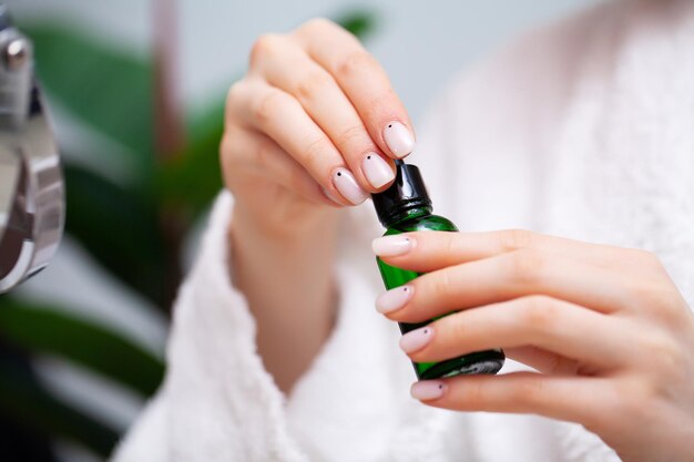 Une femme en gros plan utilise une crème liquide pour prendre soin de la peau du visage.