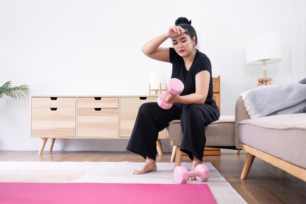 Femme grosse faisant de l'exercice à la maison une belle femme surdimensionnée dans un soutien-gorge sportif et un pantalon décontracté est assise