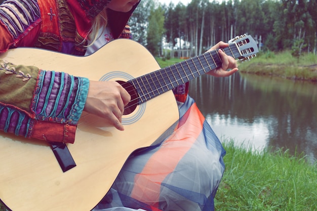 Femme avec une guitare au bord de l'eau