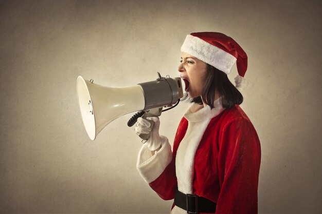 Photo femme habillée comme un père noël criant dans un mégaphone