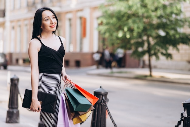 Femme habillée à la mode avec des sacs à provisions colorés dans les rues, concept d&#39;achat