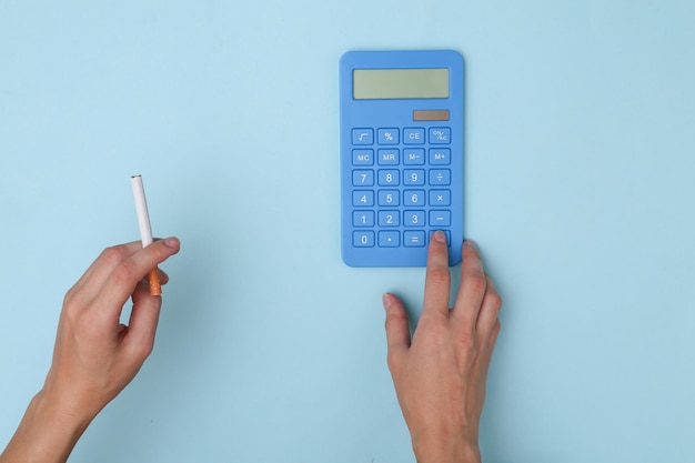 Femme hand holding cigarette et utilise la calculatrice sur fond bleu