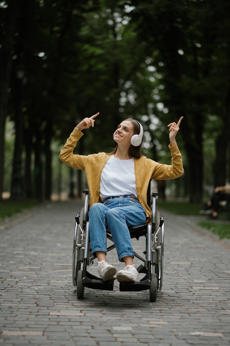 Photo une femme handicapée en fauteuil roulant écoute de la musique avec des écouteurs dans un parc d'été. personnes paralysées et handicaps, dépassement du handicap. personne de sexe féminin handicapée dans un lieu public