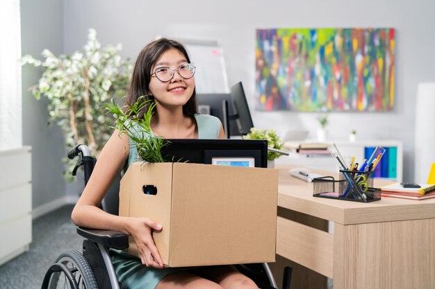 Une femme handicapée avec des lunettes et une beauté coréenne asiatique utilise un fauteuil roulant au bureau de l'entreprise