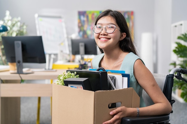 Une femme handicapée avec des lunettes et une beauté coréenne asiatique utilise un fauteuil roulant au bureau de l'entreprise