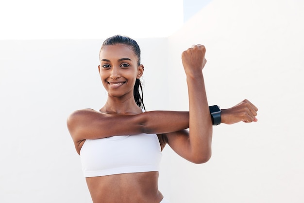 Une femme en haut blanc et short noir étire ses bras.