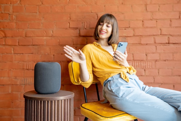 Femme avec haut-parleur intelligent et téléphone à la maison