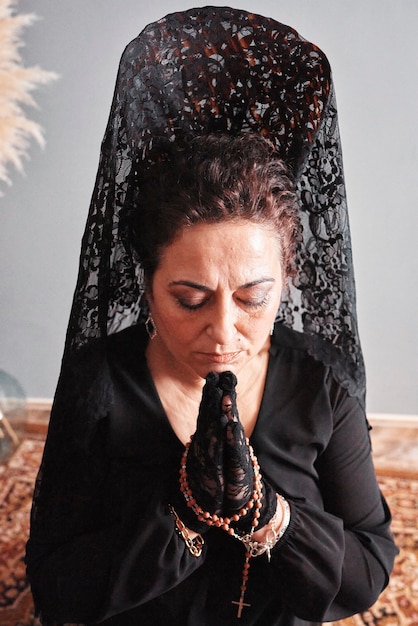 Une femme avec un haut peigne et un voile noir priant