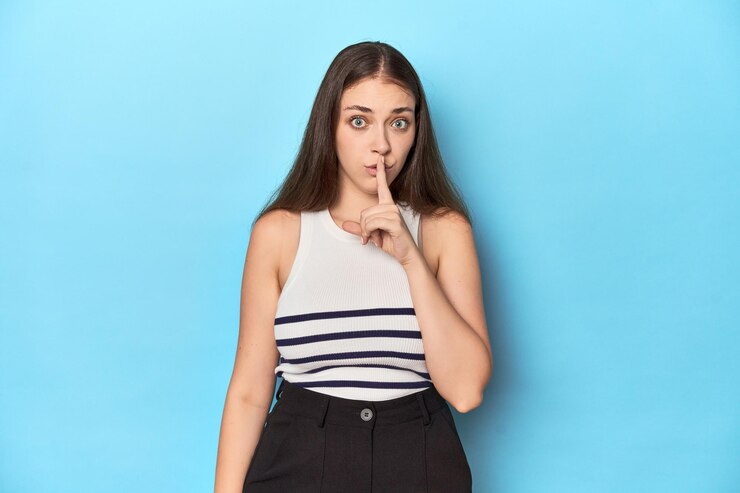Photo une femme en haut rayé posant sur un fond de studio bleu gardant un secret ou demandant le silence