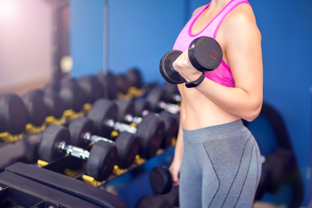 Femme en haut rose et cheveux blonds courts faisant de l'exercice avec des haltères. Concept de personnes, de remise en forme et de soins de santé