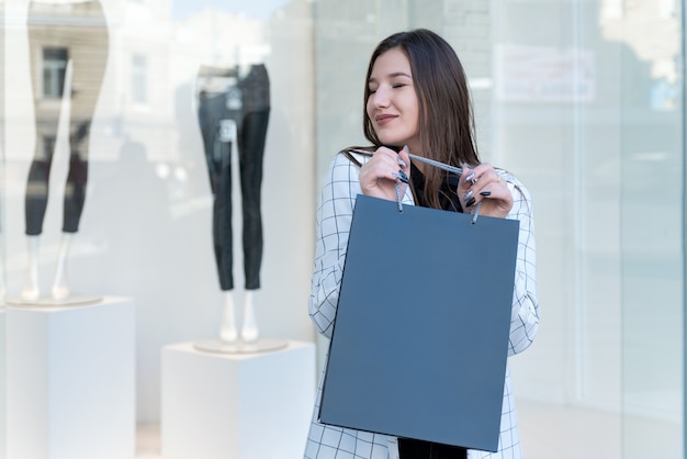 Femme heureuse avec des achats sur fond de vitrine. Vendredi noir.