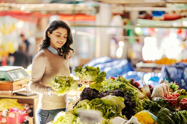 Une femme heureuse achète de la laitue au marché des agriculteurs