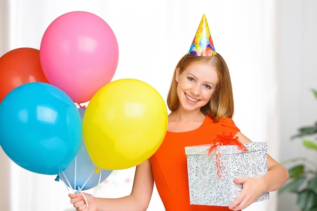La femme heureuse d'anniversaire avec des boules et un cadeau
