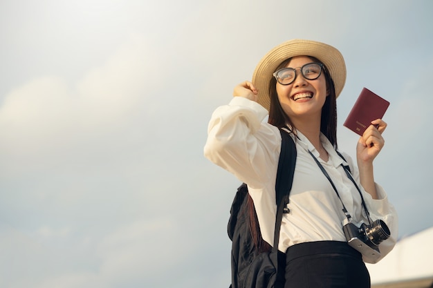 Photo femme heureuse avec appareil photo et passeport en attente de voyage en avion.