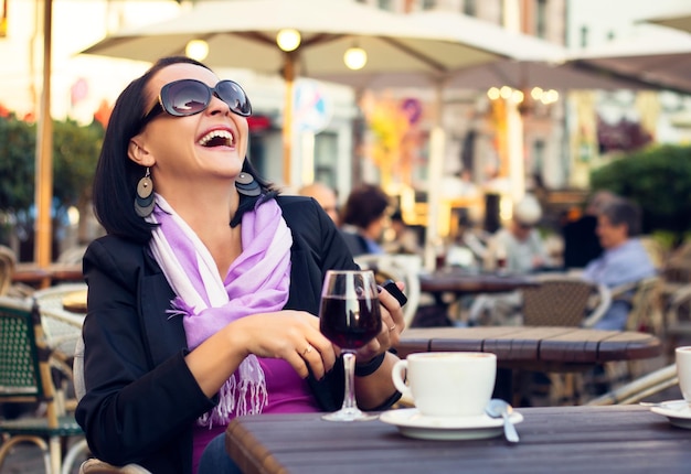 Femme heureuse appréciant la soirée avec café et vin dans un café en plein air