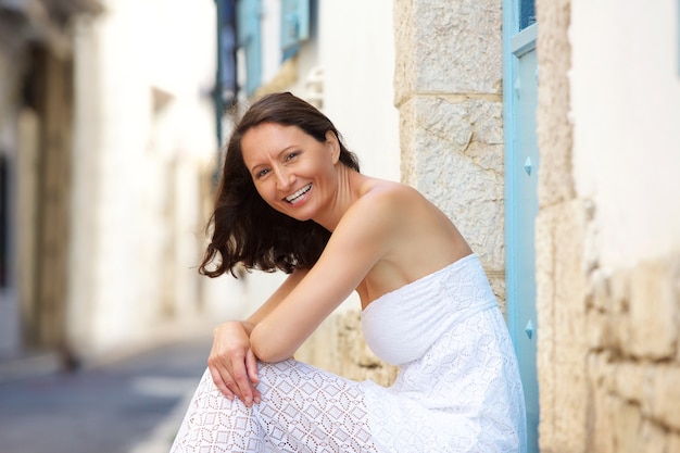 Femme heureuse assis dehors en robe d&#39;été