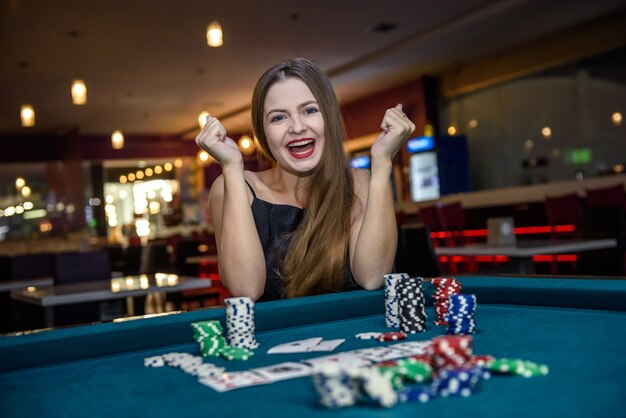 Femme heureuse au casino avec des jetons de poker et des cartes