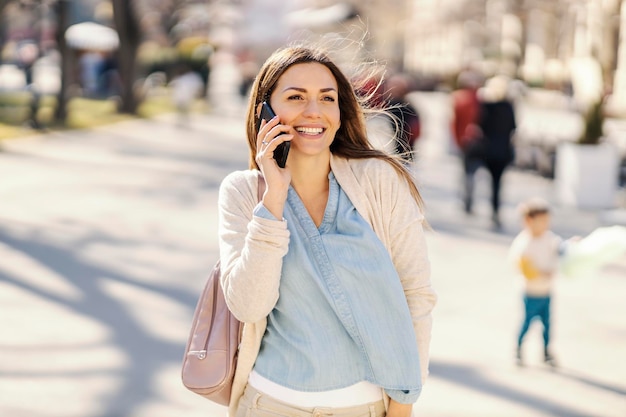 Une femme heureuse ayant une conversation téléphonique lors d'une promenade aux beaux jours dans un parc