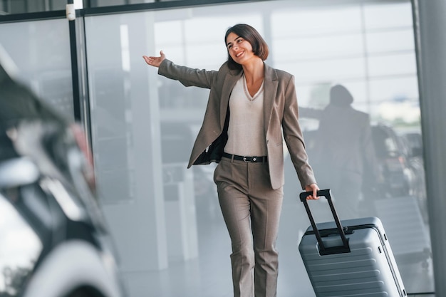 Une femme heureuse avec des bagages se tient à l'intérieur Conception du tourisme