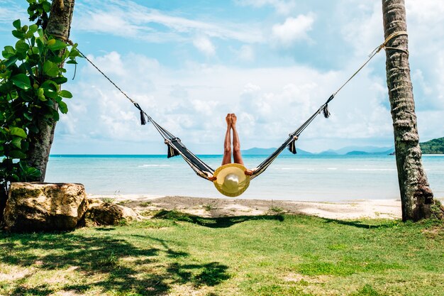 Femme heureuse en bikini noir se détendre dans un hamac