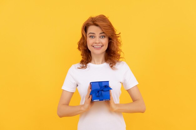 Femme heureuse avec boîte cadeau sur fond jaune shopping