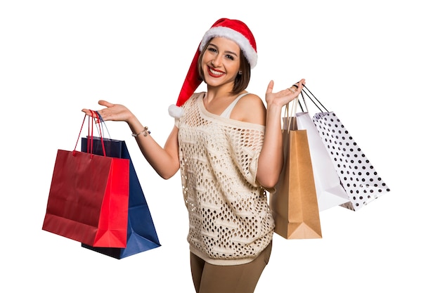 Femme heureuse avec bonnet de Noel tenant des sacs à provisions. Achat de noël