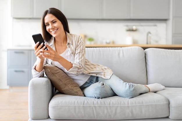 Une femme heureuse sur le canapé à la maison.