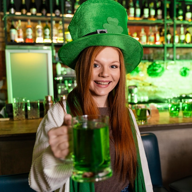 Femme heureuse avec chapeau célébrant la st. la journée de patrick au bar