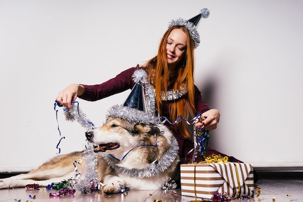 Une femme heureuse en chapeau de fête est assise à côté d'un gros chien