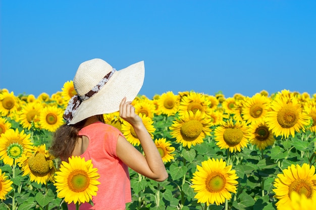 Femme heureuse avec chapeau de paille dans le champ de tournesols