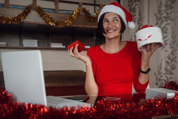 Une femme heureuse en chemise rouge est assise devant un écran d'ordinateur