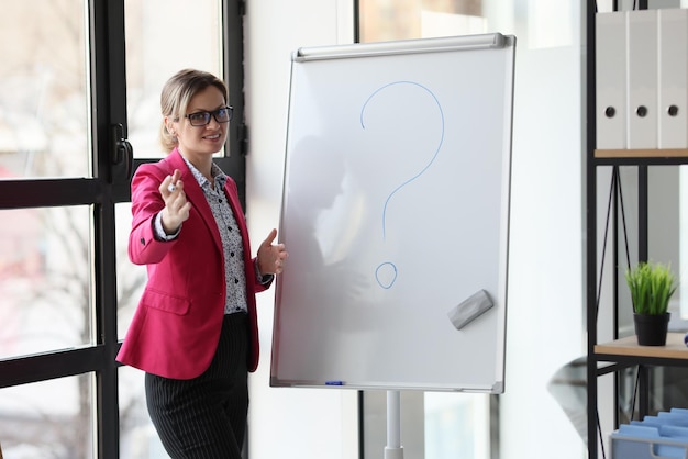 Une femme heureuse conférencière dans un bureau avec un marqueur près d'un tableau blanc un problème de concept de gros plan dans