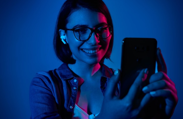 Femme heureuse dans les écouteurs communiquant via smartphone