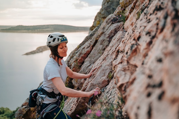 Femme heureuse dans la trentaine escaladant une montagne au coucher du soleil