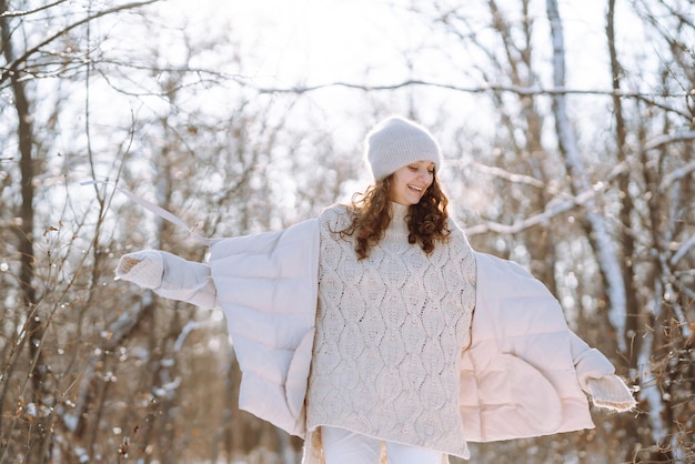 Femme heureuse dans des vêtements de style hiver marchant dans le parc enneigé Concept de voyage vacances nature