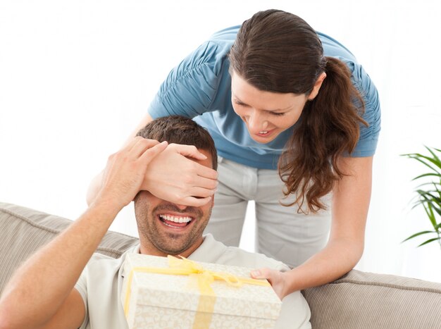 Femme heureuse donnant un cadeau à son mari dans le salon