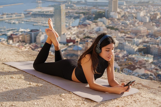 Photo une femme heureuse écoute de la musique à l'extérieur sur le fond de la ville et de la mer