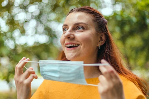 Une femme heureuse enlève son masque médical de protection de son visage en profitant de la nature et de l'air frais