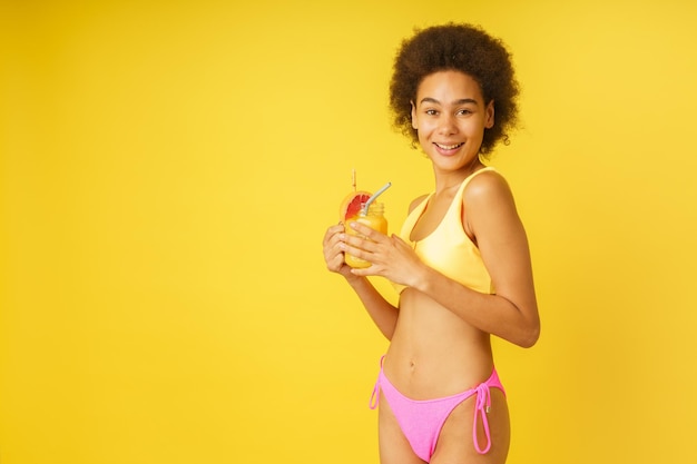 Une femme heureuse est prête pour l'été avec un maillot de bain et un cocktail