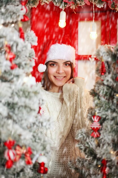 Femme heureuse et excitée sur l'arbre de Noël de scène de chute de neige avec des décorations