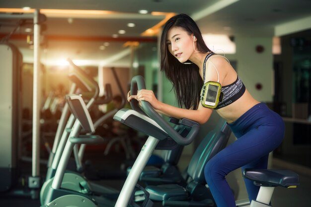 Femme heureuse, faire du vélo d&#39;exercice dans la salle de gym