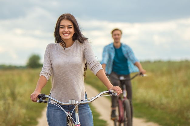 La femme heureuse faisant du vélo près de l'homme en plein air