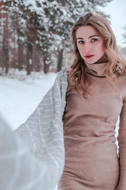 Femme heureuse sur le fond de la forêt d'hiver. Jeune jolie fille dans les bois à l'extérieur. Portrait d'une belle femme joyeuse. Mode d'hiver. Robe avec foulard