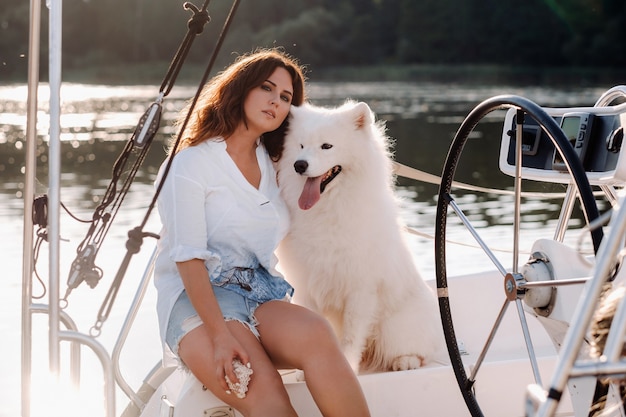 Une femme heureuse avec un gros chien blanc sur un yacht blanc dans la mer