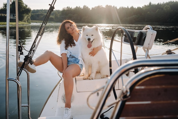 Une femme heureuse avec un gros chien blanc sur un yacht blanc dans la mer.