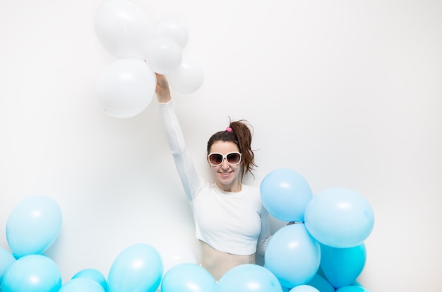 Femme heureuse à lunettes sourit et tient des ballons bleus dans ses mains