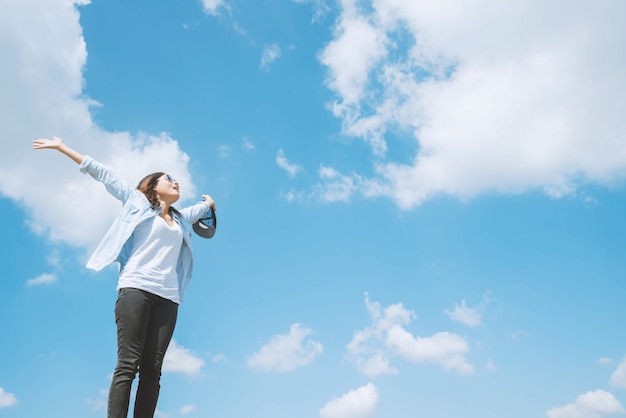 Femme heureuse avec les mains debout sur le rocher et le lagon au coucher du soleil